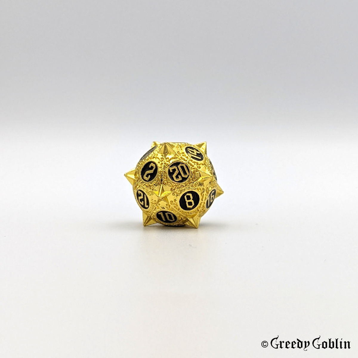 Metal D20 from DnD dice set with sharp edges and gold finish. The engravings behind the numbers are black.