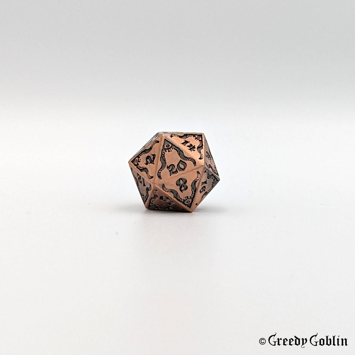 Brushed copper Cthulhu D20 from DnD dice set, with black engravings and numbers.