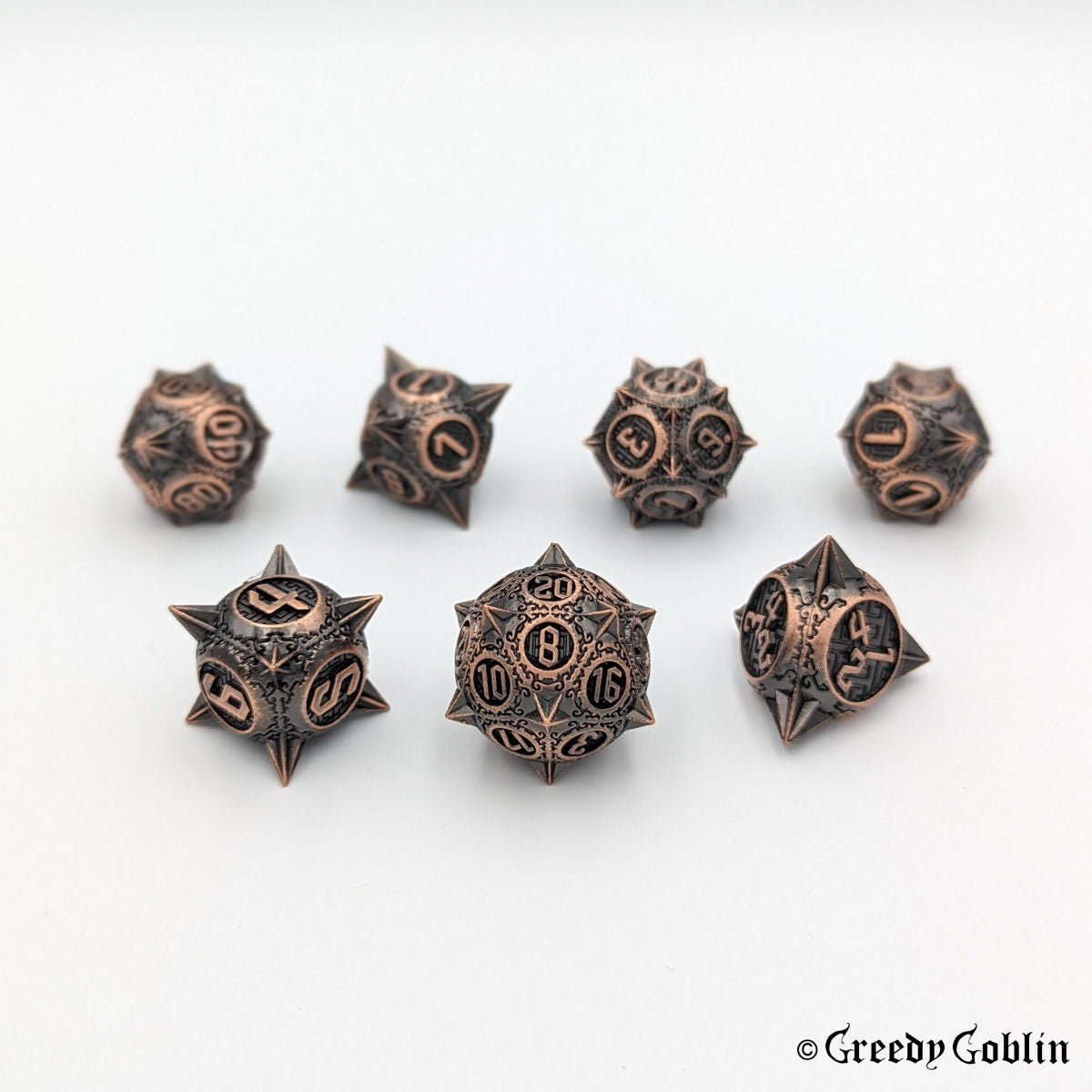 Metal DnD dice set (D4, D6, D8, D12, D20, 2x D10) with sharp edges and copper finish.