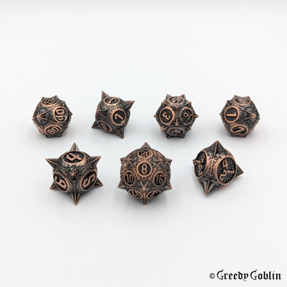 Metal DnD dice set (D4, D6, D8, D12, D20, 2x D10) with sharp edges and copper finish.