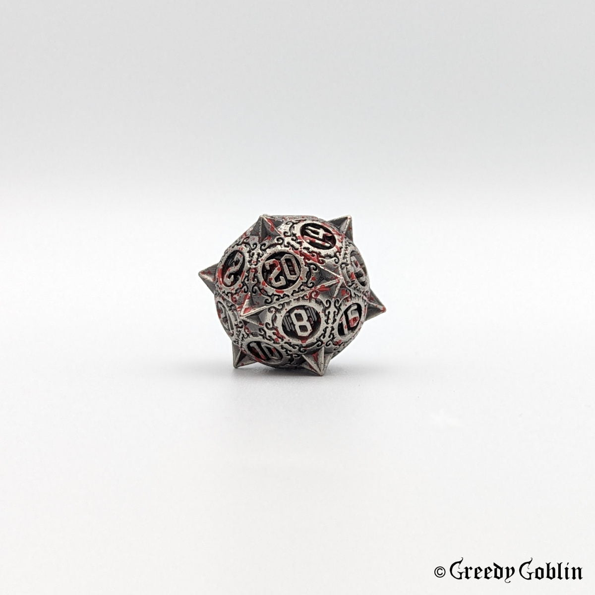 Metal D20 with sharp edges and red splatters from DnD dice set.