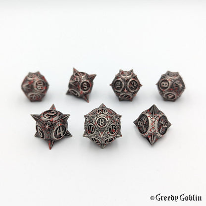 Metal DnD dice set (D4, D6, D8, D12, D20, 2x D10) with sharp edges and red splatters.