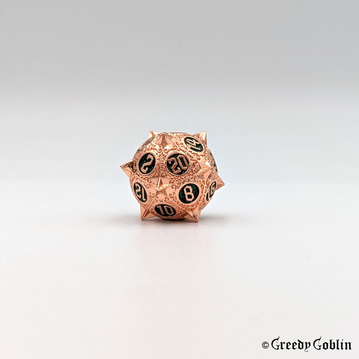 Metal D20 from DnD dice set with sharp edges and copper finish. The engravings behind the numbers are deep green.