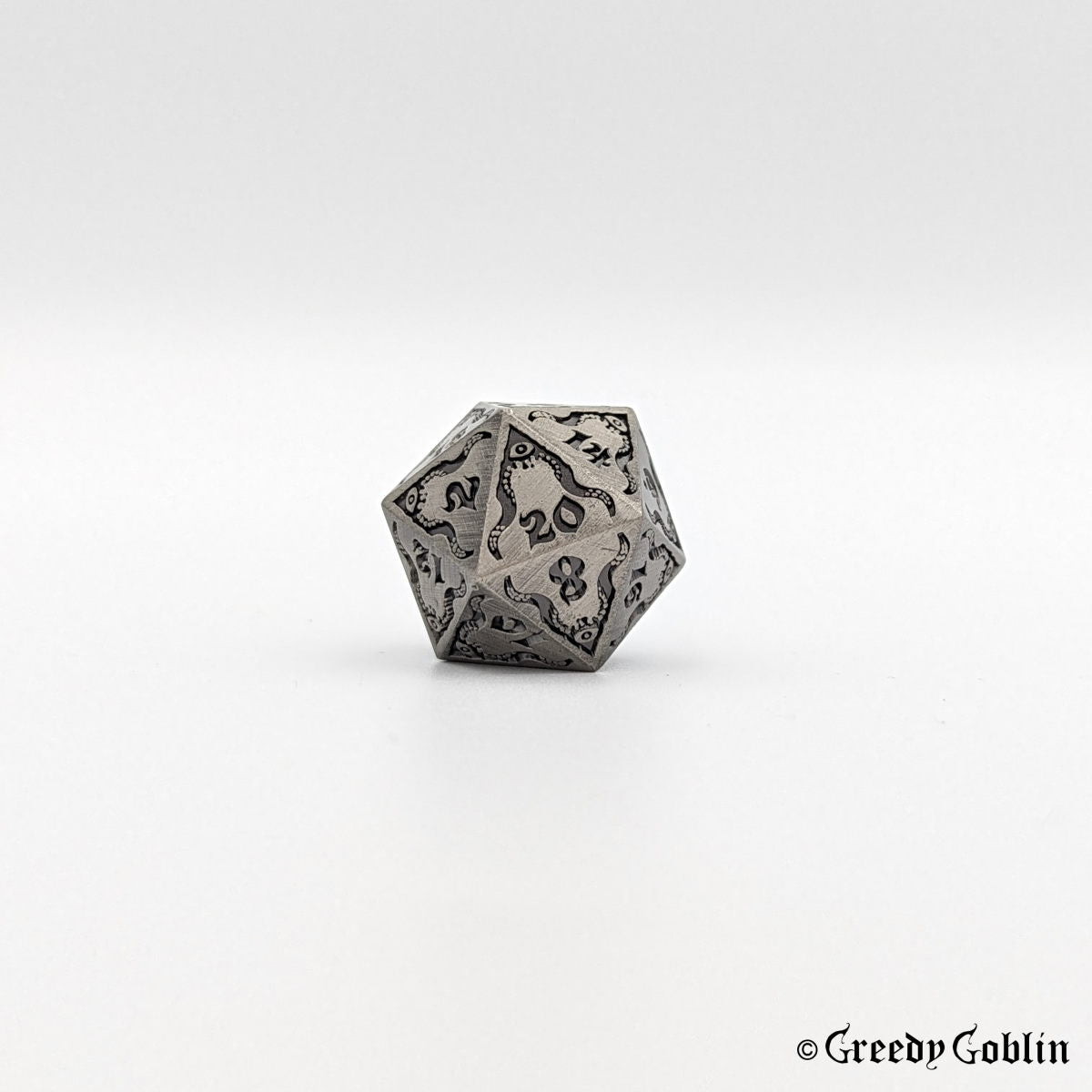 Brushed metal Cthulhu D20 from DnD dice set, with black engravings and numbers.